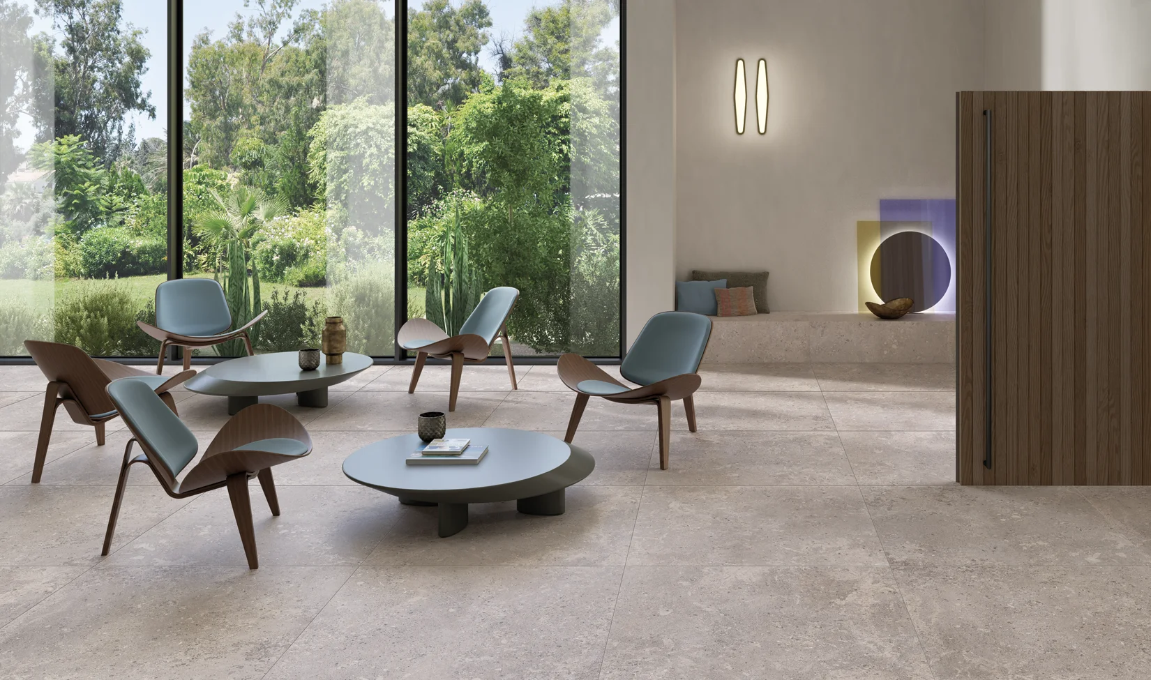 Interni moderni con pavimento in pietra grigia della collezione Omnia colore Devix Greige, arredamento minimalista e vista sul giardino attraverso ampie vetrate.