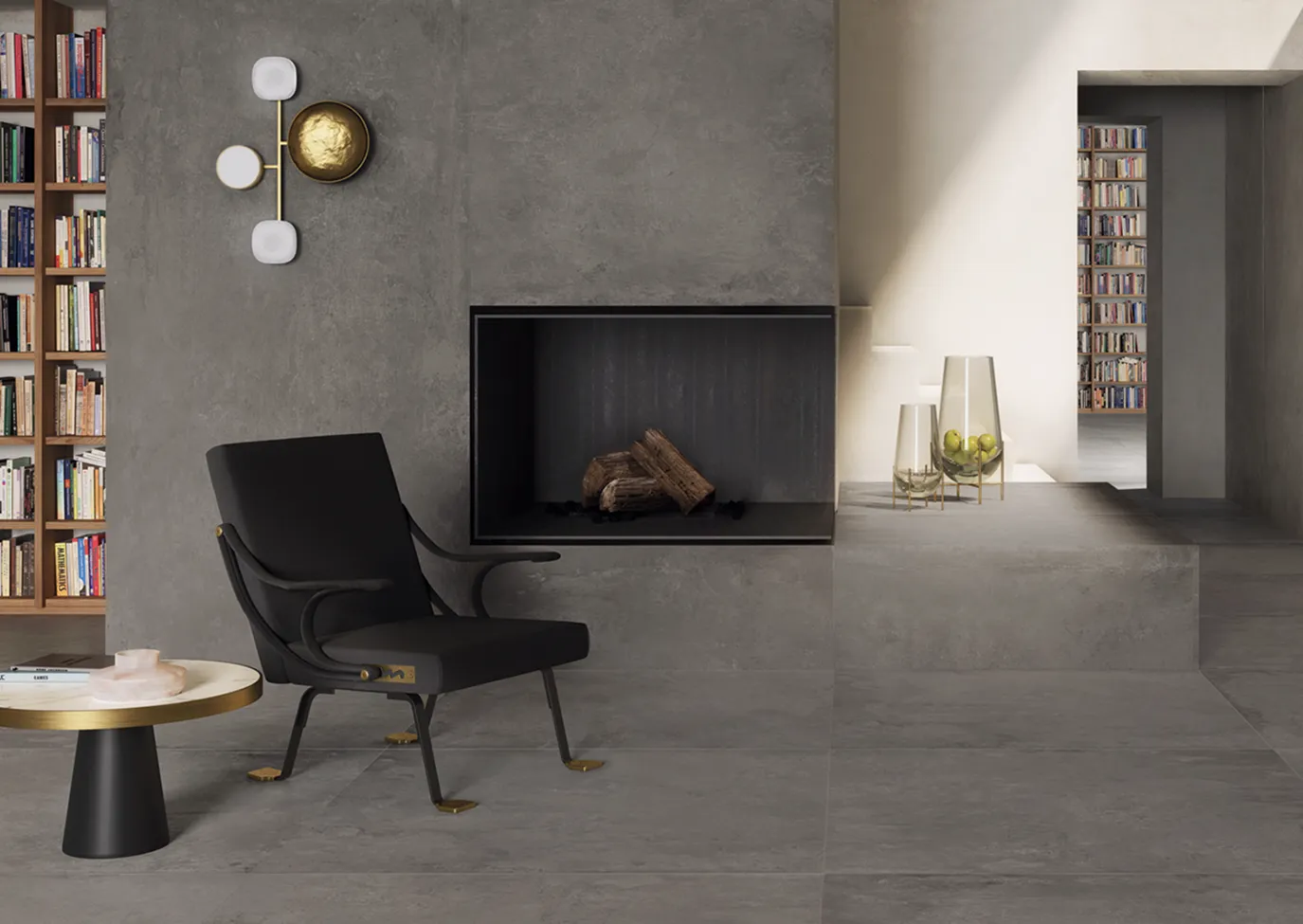 Pavimenti e parete rivestiti con piastrelle in gres porcellanato effetto cemento grigio scuro della collezione Ikon in un soggiorno moderno con camino e libreria.