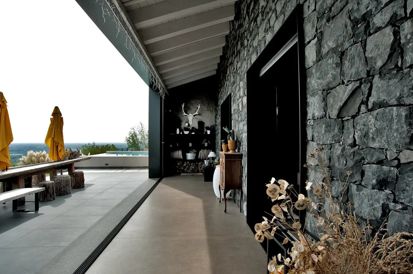Terrazza elegante con piastrelle effetto cemento colore Ivory della collezione Moov, parete in pietra e vista mare.