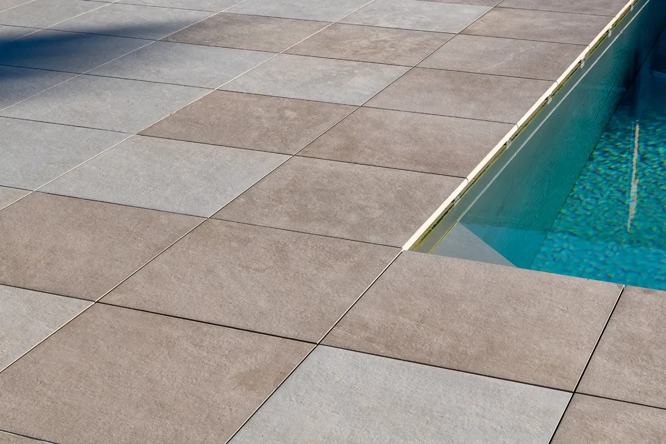 Bordo piscina con pavimentazione in gres porcellanato antiscivolo effetto pietra.