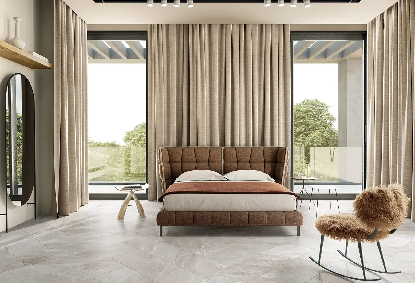 Camera da letto luminosa con pavimento effetto pietra collezione Ubik colore greige, letto capitonné e ampie finestre.