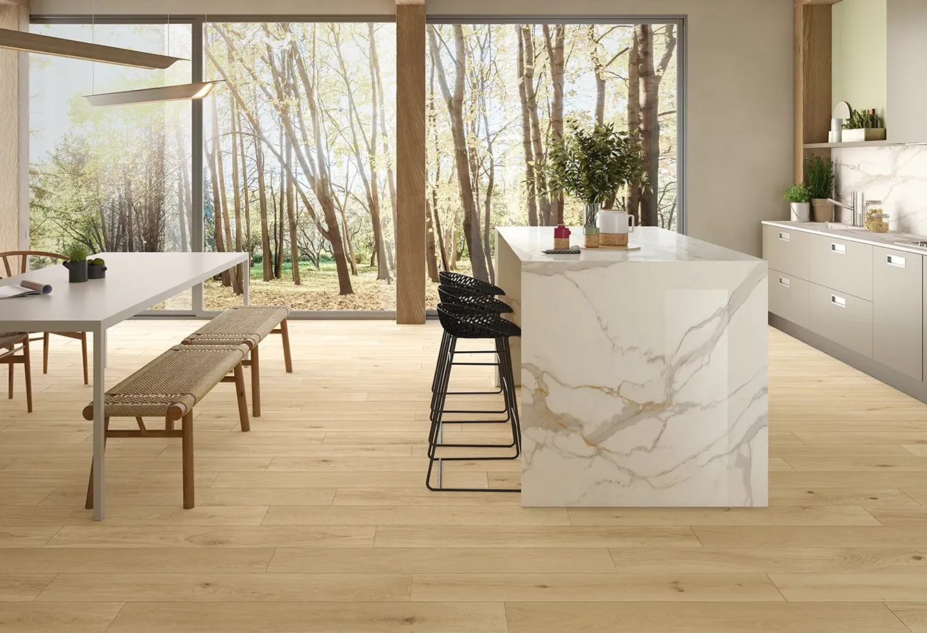Cucina luminosa con pavimento effetto legno, isola centrale e piano di lavoro effetto marmo bianco.