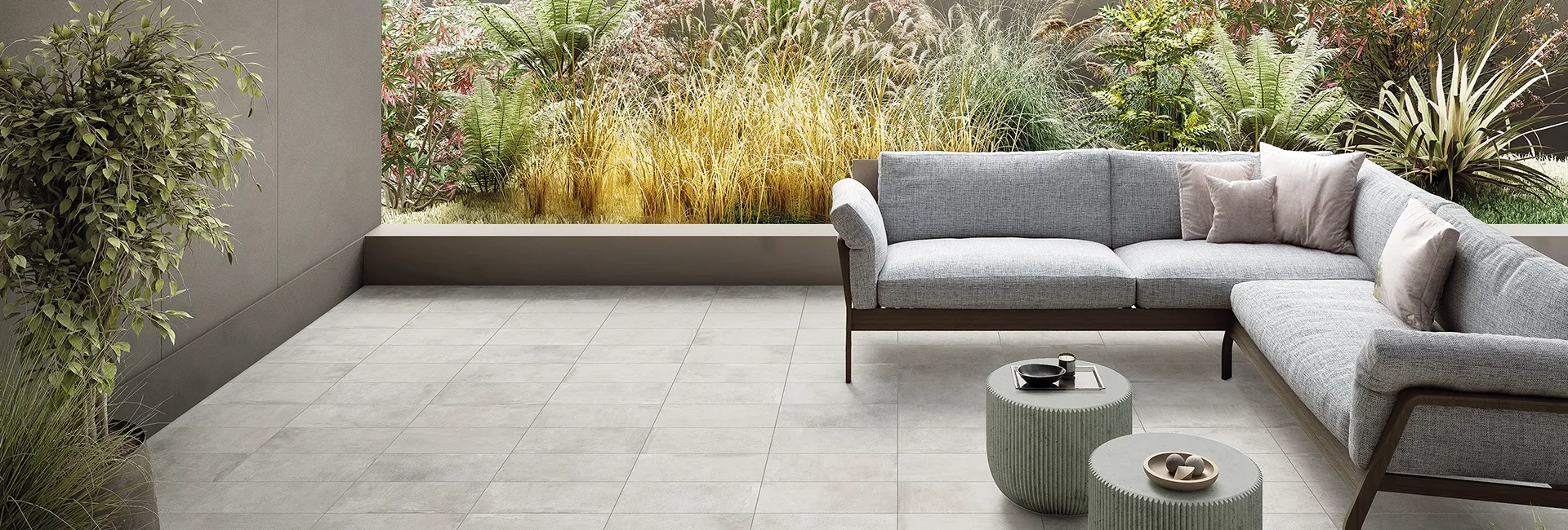 Пол из керамогранита эффекта цемента Street цвета Milano Silver на террасе с диваном и садом.