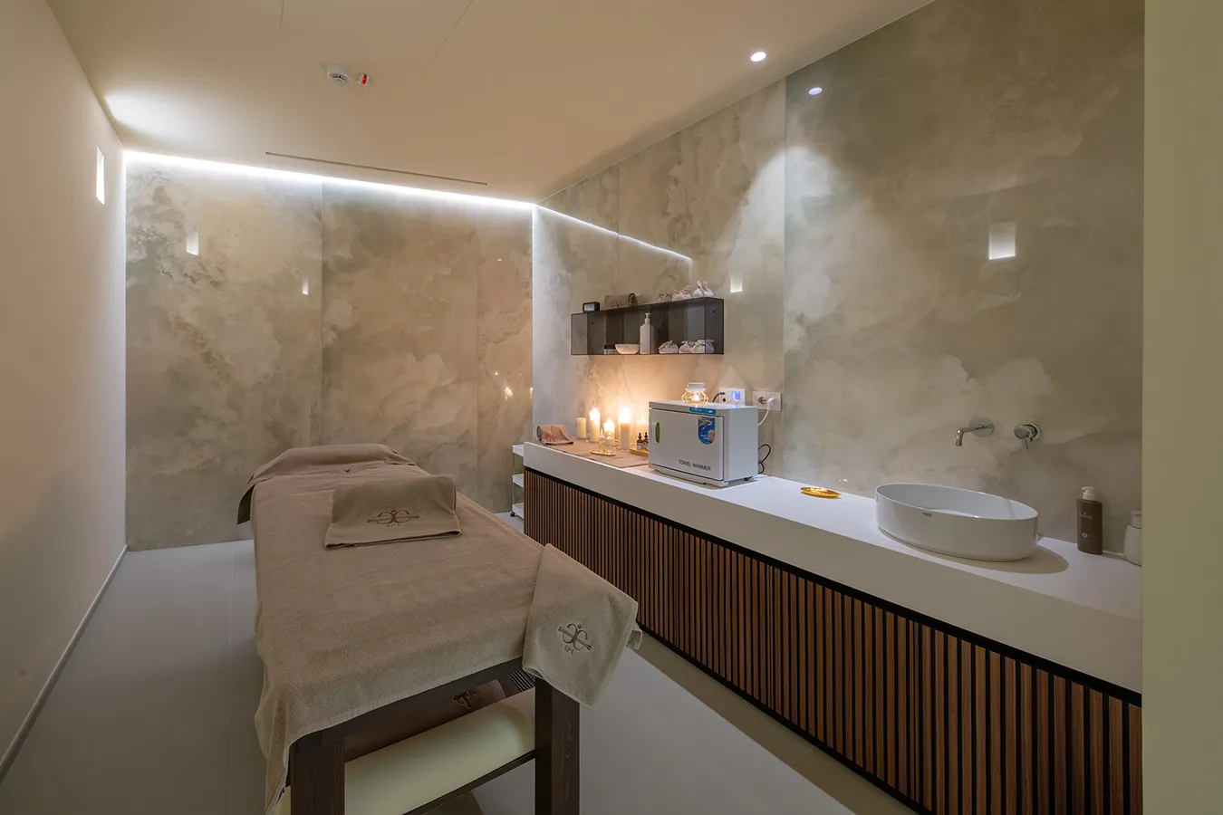 Refined SPA treatment room with onyx marble effect porcelain stoneware, soft lighting, and meticulous details for a luxurious wellness experience.