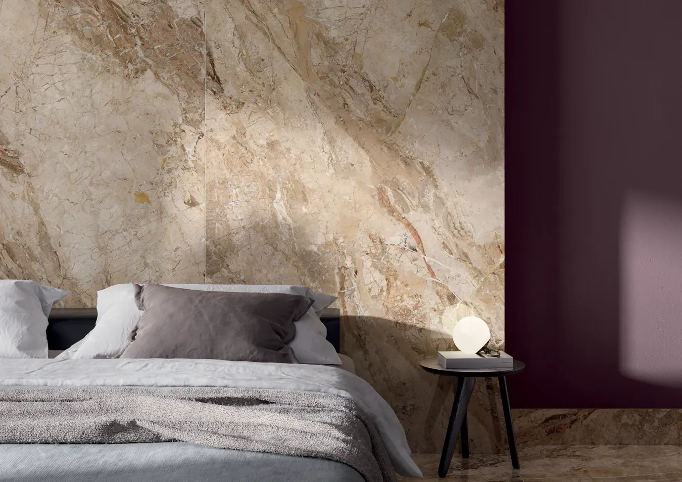 Camera da letto contemporanea con pavimenti e parete dietro il letto effetto marmo beige, arredamento minimalista e poltrona accentata vivace.