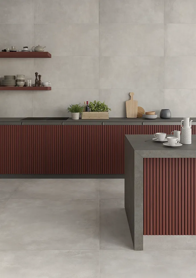 Cucina moderna con pavimento in gres porcellanato effetto metallo e isola con dettagli in rovere rosso.