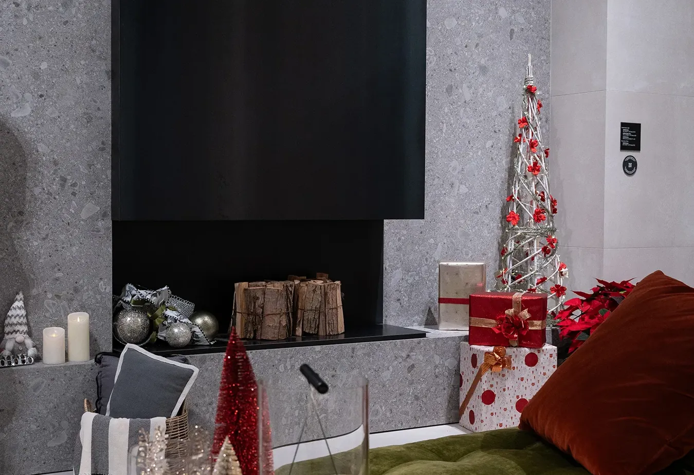 Salon festif avec cheminée, carreaux Noord blancs et décorations de Noël rouges et argentées.