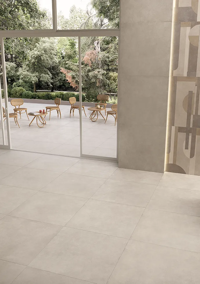 Open and airy space highlighted by Geo collection tiles in Silver color, defining the elegance of an indoor dining area extended towards a lush outdoor setting.