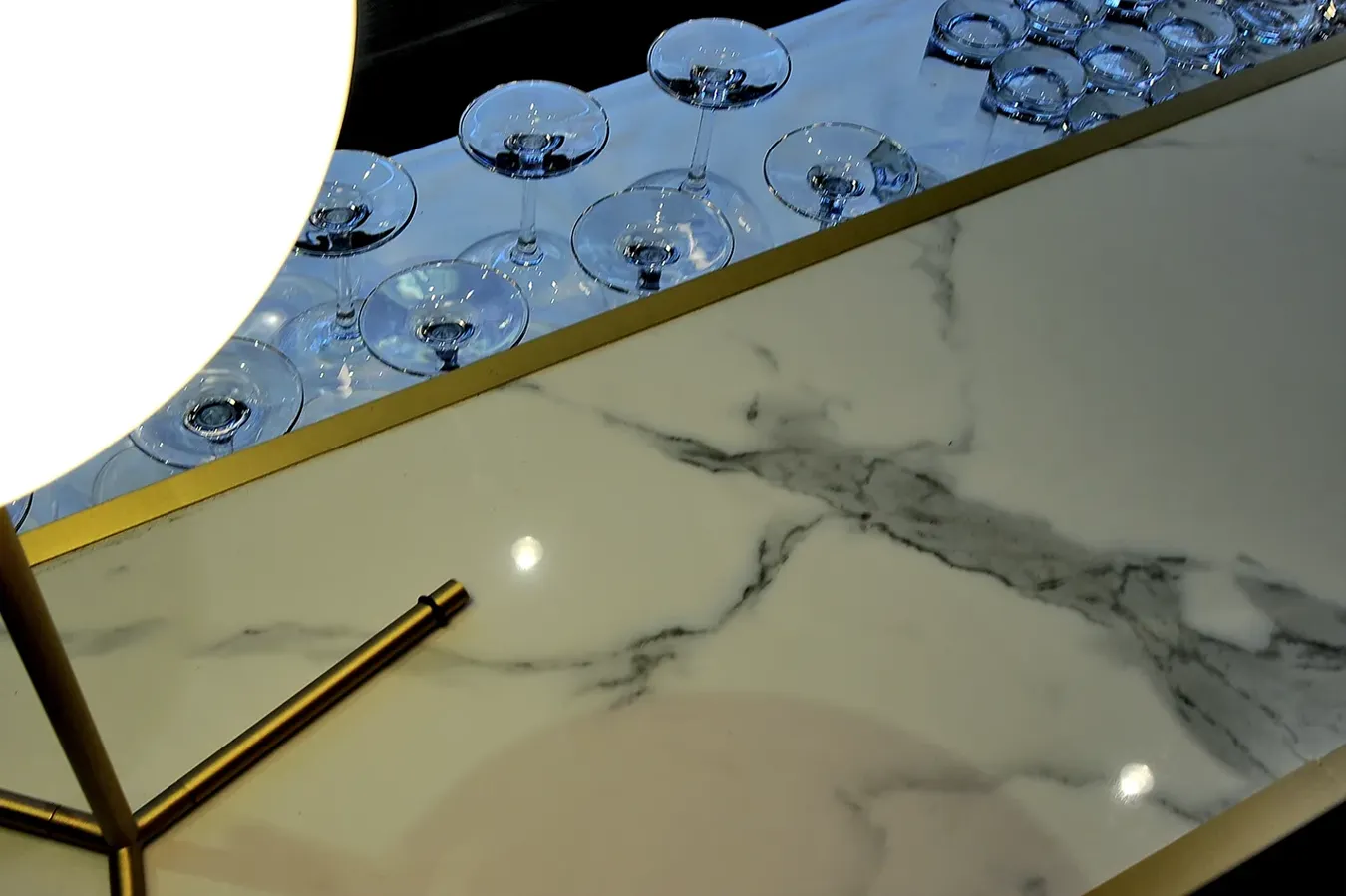 Gros plan de grès cérame effet marbre Calacatta avec reflets de lumière.