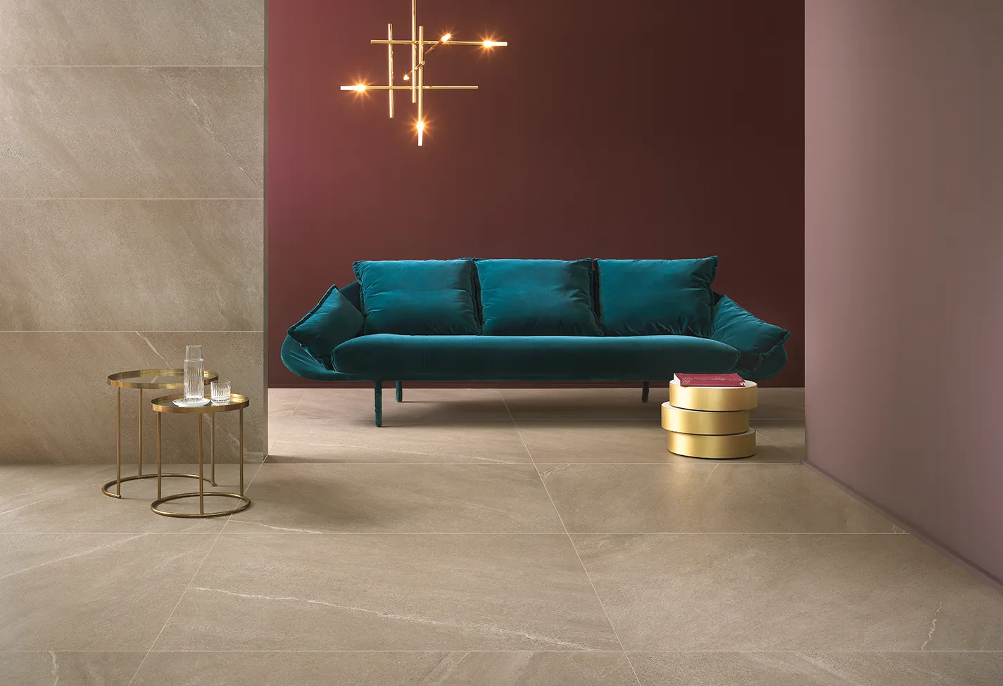 Pavimenti e parete con piastrelle in gres porcellanato effetto pietra colore beige, in un elegante soggiorno con divano azzurro.